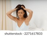 Small photo of Attractive girl headache, it's time to get up for work. Beautiful young woman, dressed in silk negligee of delicate blue color, is sitting in cozy bed in the bedroom, holding her head.