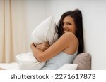Small photo of Beautiful slender young woman, dressed in gently light blue silk nightie negligee, lies in cozy bed in the bedroom. Attractive girl hugs pillow after waking up from sleep. Good morning.