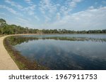 A peaceful view of Lake Defuniak in Defuniak Springs, Florida, on a spring day with the sky reflecting in the water and a walkway.