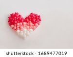 Heart of pink balloons on a white wall.