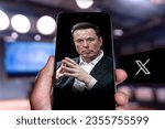 Small photo of Man hand holding Phone displaying Elon musk photo on the screen, x logo on the background Twitter has officially rebranded to X after owner Elon Musk changed its bird logo. Qatar, September 1, 2023