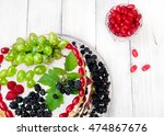 Cake with whith, fruits (grape) and berries (raspberry and blackberry,cornel dowwood)on top as decoration.Crystal glass near with dogwood(cornel) berriesHomemade fresh cake. Top view.