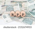 Small photo of Word RPP written in polish with wooden blocks standing on money, "RPP" is a shortcut for The Monetary Policy Council