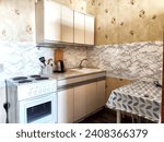 Small photo of The interior is small old kitchen with a table, stool, cabinets, sink and stove. Design in the Soviet poor outdated style