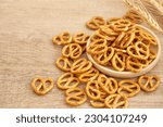 Small photo of mini salted pretzel in bowl on wood table background. mini salted cracker pretzel background. salty, mini snack, appetizer, pretzel