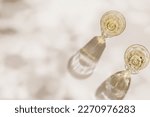 Small photo of Top view of wineglasses with white wine, leaves shadow and glare from glass at sunlight, summer alcohol drink background beige monochrome, creative aesthetic view of wine glass goblets style on table