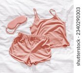 Small photo of Top view pink pajama and eye sleep mask on white crumpled bedclothes. Cozy pyjamas for comfort rest at night. Flat lay from singlet, shorts, sleeping mask pastel pink color, sleep well concept