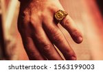 Small photo of large signet ring with a $ symbol on the male hand