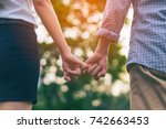 Small photo of Young love couple walking in the autumn park holding hands looking at sunset scence. Young love couple pinky promise or pinky swear.