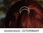Small photo of Woman's hairstyle. A beautiful hairpin in her hair. Tender shiny crescent hairpin. Red-red hair.