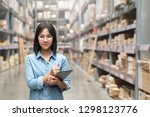 Young attractive asian worker, owner, entrepreneur woman holding smart tablet looking at camera with concept efulfillment service business warehouse management stock online. Asian sme merchandise.