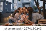 Small photo of Mother's day two young child cuddle hug give flower gift box to mature mum. Love kiss mom asia people middle aged adult at home cozy dining table night dinner party happy smile enjoy relax warm time.