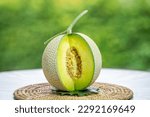 Small photo of Crown Musk Melon on blurred greenery background, Cantaloupe Crown Melon fruit in Bamboo mat on wooden table in garden.
