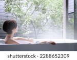 Small photo of A woman relaxing in a bathtub at a ryokan or hotel. For images of hot springs, etc.