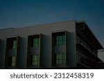 Small photo of A unassuming office block displays strong lines, an olive green hue and green window reflections in the early evening