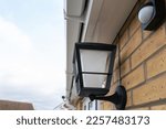 Shallow focus of a newly installed, multi colour smart lighting lantern outside the rear door of a house. A nearby PIR sensor is also seen.