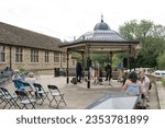 Small photo of St Ives, Cambridgeshire, UK - 27 April 2023: Live music artists seen preparing their equipment under a bandstand area on the famous market town. People can be sen gathering for the free music.