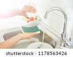 Small photo of woman without gloves or washing dishes with a sponge. gel and foam for washing dishes. dirty dishes in the kitchen.