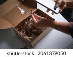 Small photo of woman opens a delivery box from a store and discovers a broken glass. An improperly packed item crashed on delivery