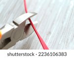 Small photo of Electrician cuts electrical wires with pliers. Cutting pliers and cable. A cutter is cuting electrical wire or cable. Cutting wires with clippers. Metal nippers.