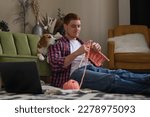 Small photo of ginger man with freckles skillfully knitting at home, while his Beagle dog attentively watches the process. concept the versatility of modern masculinity and the value of companionship with pets.
