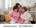 Small photo of Three radiant women from different generations embrace and enjoy each other's company, laughing together in a cozy living area. Breaking down generational barriers for a more cohesive family unit.