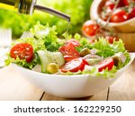 olive oil pouring into bowl of salad