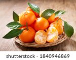 Fresh mandarin oranges fruit or tangerines with leaves on a wooden table