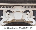 Small photo of CARVED STONE FEATURE DOORWAY BULKHEAD A closeup sandstone entrance design with decorative curled flourishes swirl design bordered in a light natural rock color with long thin dark textured bricks