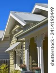 Small photo of PERIOD STYLE HOME FEATURING DECORATIVE FRETWORK TRIMS - A olive green colored timber siding weatherboard house with white detailed ornate supports and shade awning, a patio verandah with iron roofing