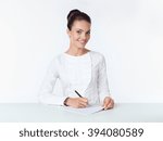 Small photo of the business woman sits at a white table and holds the handle ilist of paper