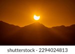 Small photo of An awe-inspiring photo of a solar eclipse viewed from a mountainous landscape. The dark silhouette of the moon obscures the sun, creating a striking halo effect around the edges of the eclipse.
