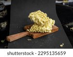 Small photo of Block of uncooked noodles with a wooden butting block on a black background in studio