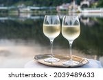 Tasting of white quality riesling wine served on outdoor terrace in Mosel wine region with Mosel river and old German town on background in sunny day, Germany