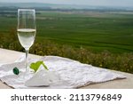 Small photo of Glass of white brut blanc de blancs champagne wine and examples of vineyard soils, white chalk stone, view on grand cru vineyards of Cote des Blancs near Avize, Champagne, France