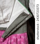 Small photo of Austrian traditional dirndl with low neckline, close up. Grey bodice, pink skirt having floral pattern print, white cotton blouse and lining. Row of sewed fasteners: hooks and eyes type. Ethnic style