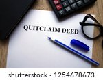 Small photo of Quitclaim deed form, pen, glasses and calculator on desk