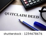 Small photo of Quitclaim deed form, pen, glasses and calculator on desk