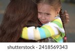 Small photo of little child cries, tears child face, mother calms capricious kid girl daughter, happy family, wipe tears face, hug kid park, discussing reasons, trying control process, devaluation child experiences