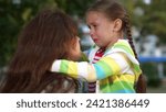 Small photo of little child cries, tears child face, mother calms capricious kid girl daughter, happy family, wipe tears face, hug kid park, be sad let go, control fear resentment, guilty, tears child eyes
