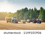 Agricultural machinery on a chamfered golden field moves bales of hay after harvesting grain crops. Tractor loads bales of hay on trailer. Harvest concept