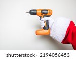 Santa Claus hands using an orange colored drill