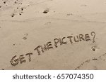 Small photo of Handwriting words "GET THE PICTURE?" on sand of beach.