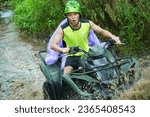 Small photo of it's very exciting to play atv in bali, with the terrain of village roads, waterfalls, and rice fields. the man in the green shirt is very excited to pass the muddy terrain. riding a child in a purple