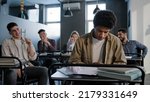 Small photo of Unhappy african american student loser feeling mocking bullying anger from classmates suffering from abuse young upset distressed guy sits alone in classroom at desk discrimination and racism concept