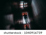 Small photo of View from behind of silhouette of man entrepreneur having phone talk while moving away inside of dark office hall with multiple glass and mirror reflections, and strong chromatic aberrations