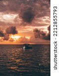Small photo of A vertical seascape with a stunning evening sky on the sunset and a silhouette of a safari diving yacht swinging on the waves aloof; a golden hour skyscape in the ocean with a boat on the water