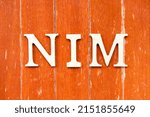 Small photo of Alphabet letter in word NIM (Abbreviation of Net interest margin) on old red color wood plate background