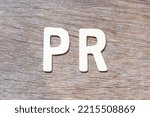 Small photo of Alphabet letter in word PR (Abbreviation of purchase requisition or public relations) on wood background