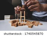 A man try to rebuild wooden blocks tower after them breakdown on white table 